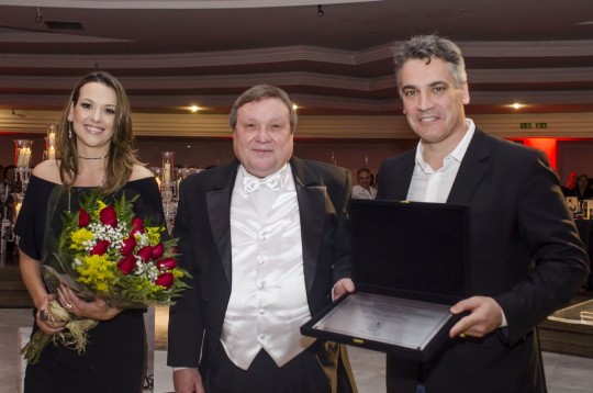 O casal Renato Ramalho e Laura Fagundes Ramalho, presidente e primeira-dama do Clube Curitibano homenageiam o maestro Jaime Zenamon (ao centro) com um placa alusiva ao evento