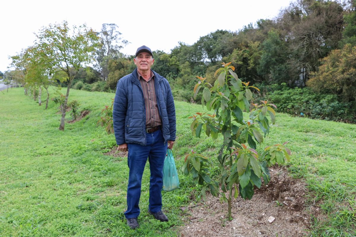 Morador de Pinhais ao lado de uma das árvores frutíferas que plantou