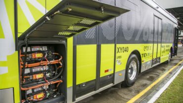Foto mostra o novo ônibus 100% elétrico e o compartimento onde ficam as baterias com a porta aberta