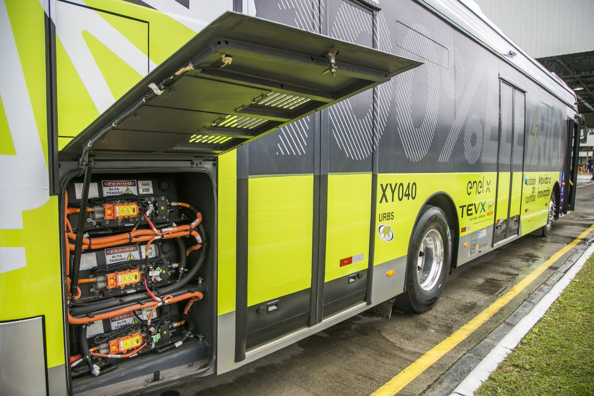 Foto mostra o novo ônibus 100% elétrico e o compartimento onde ficam as baterias com a porta aberta