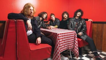 Imagem mostra integrantes da banda australiana Sticky Fingers sentados à mesa de um bar