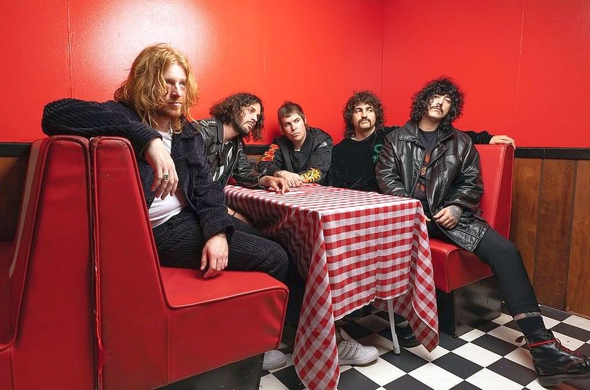 Imagem mostra integrantes da banda australiana Sticky Fingers sentados à mesa de um bar