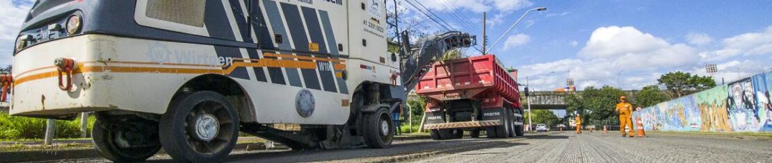 A imagem mostra uma máquina da prefeitura de Curitiba realizando a retirada do asfalto antigo para a colocação de um novo no bairro Jardim Botânico, em Curitiba.