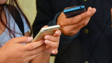 Imagem mostra duas pessoas acessando o celular para ler mensagens.