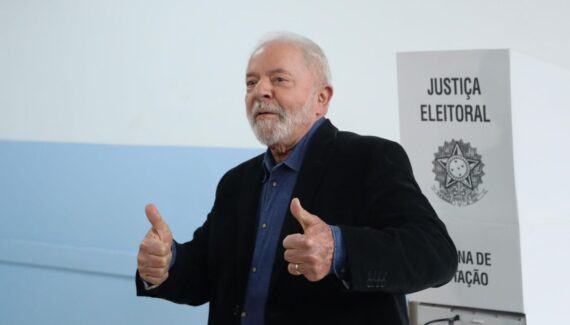 Imagem de Lula votando em frente à cabina eleitoral, fazendo sinal de positivo
