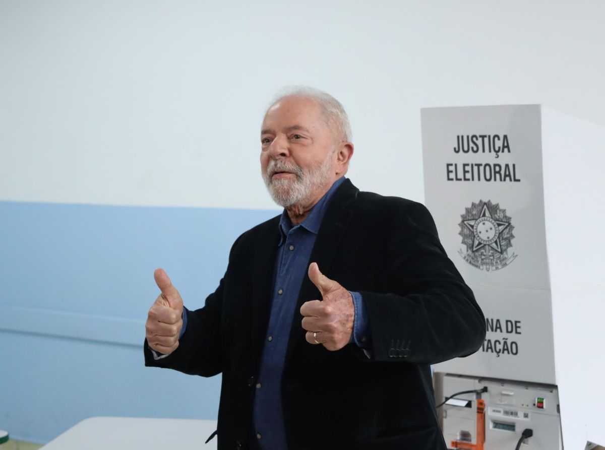 Imagem de Lula votando em frente à cabina eleitoral, fazendo sinal de positivo