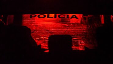 Imagem mostra uma viatura da Polícia Militar do Paraná em um contraluz, com tom vermelho e preto.