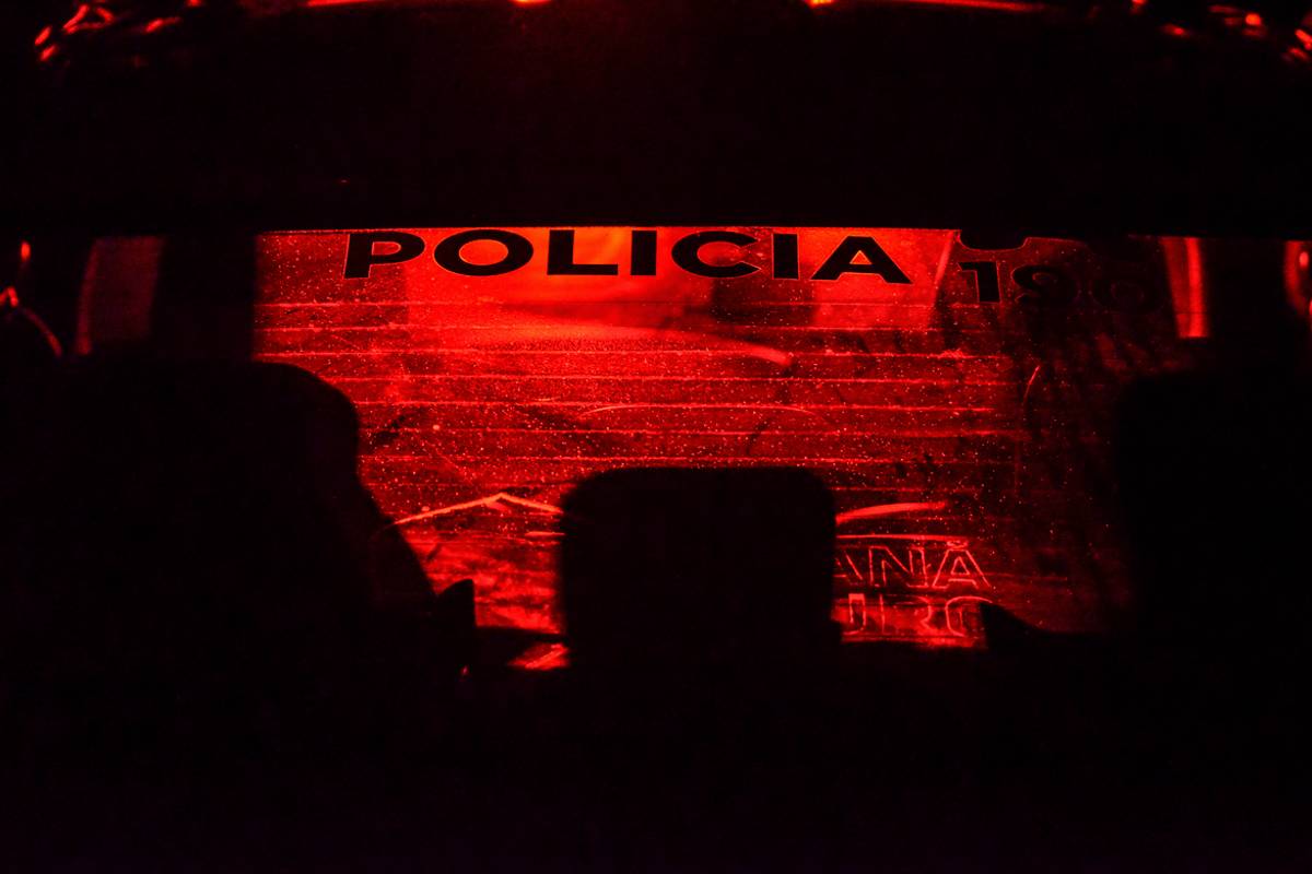 Imagem mostra uma viatura da Polícia Militar do Paraná em um contraluz, com tom vermelho e preto.