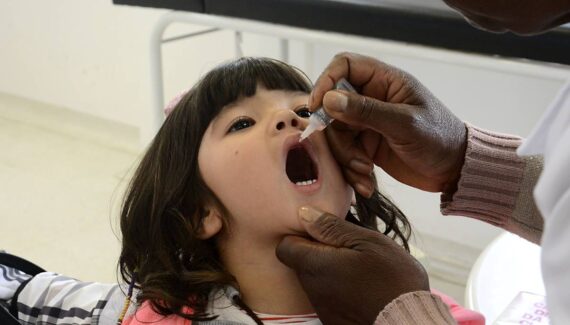 Imagem mostra uma criança de Curitiba tomando as gotinhas contra a poliomielite