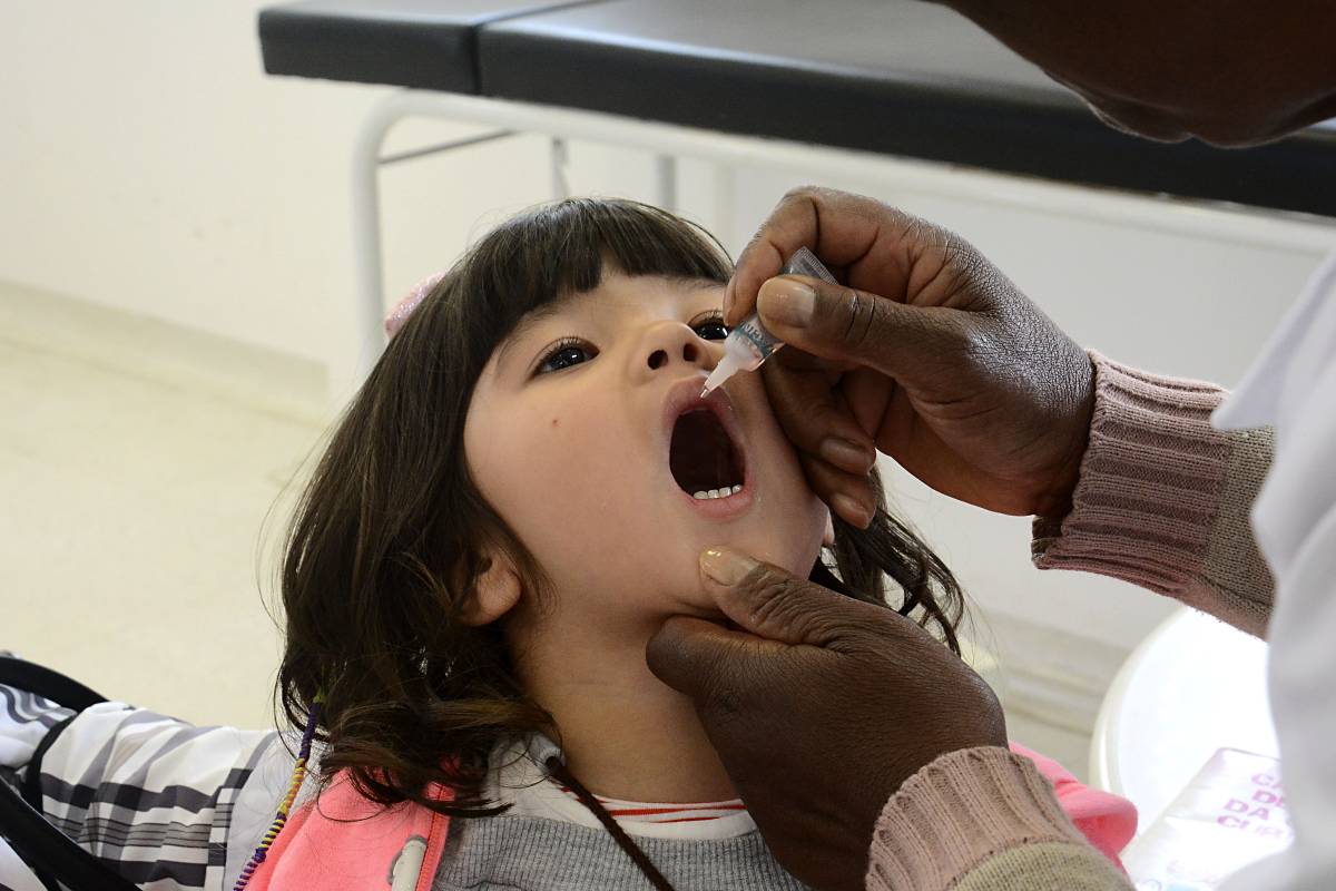 Imagem mostra uma criança de Curitiba tomando as gotinhas contra a poliomielite
