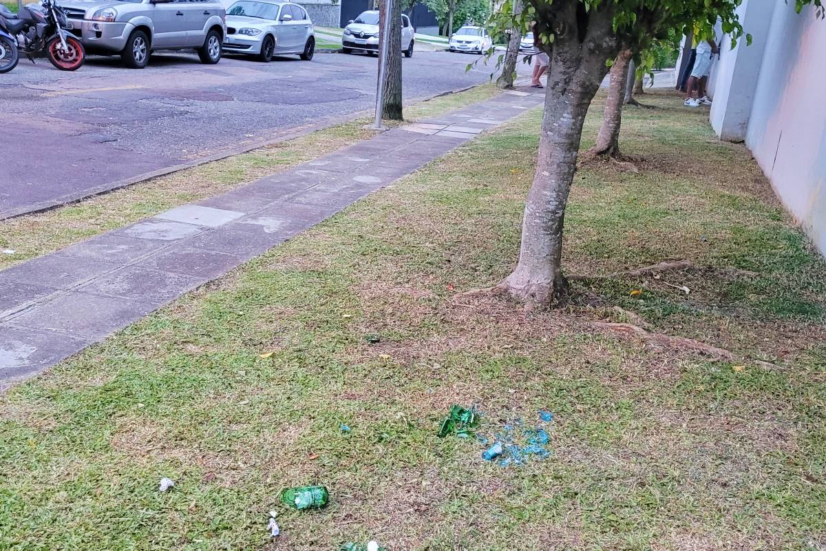 Imagem mostra um flagra feito no final de semana mostra garrafas de cervejha quebradas no gramado e um homem urinando em uma das casas da vizinhança da praça.