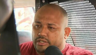 Nilson Pedro dos Santos está dentro de um carro da polícia dando entrevista para a imprensa de Curitiba