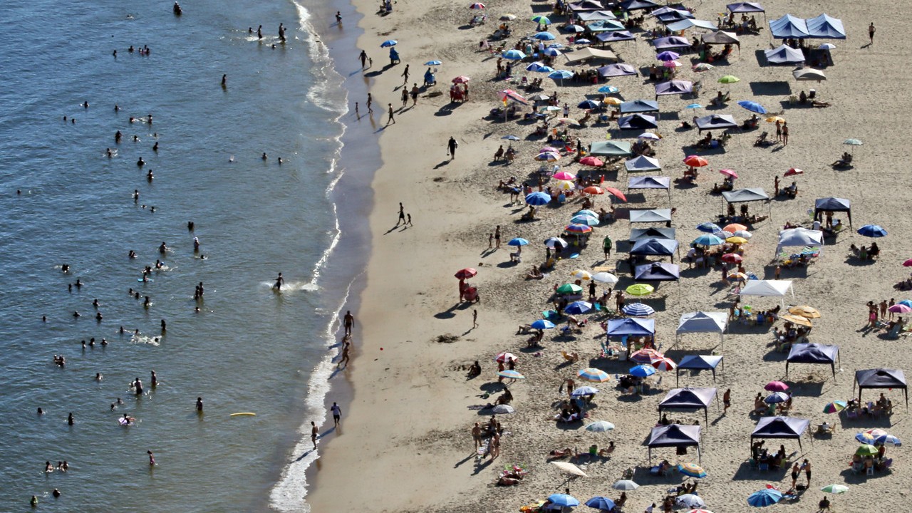 Veranistas na praia de Guaratuba, no mar e na areia