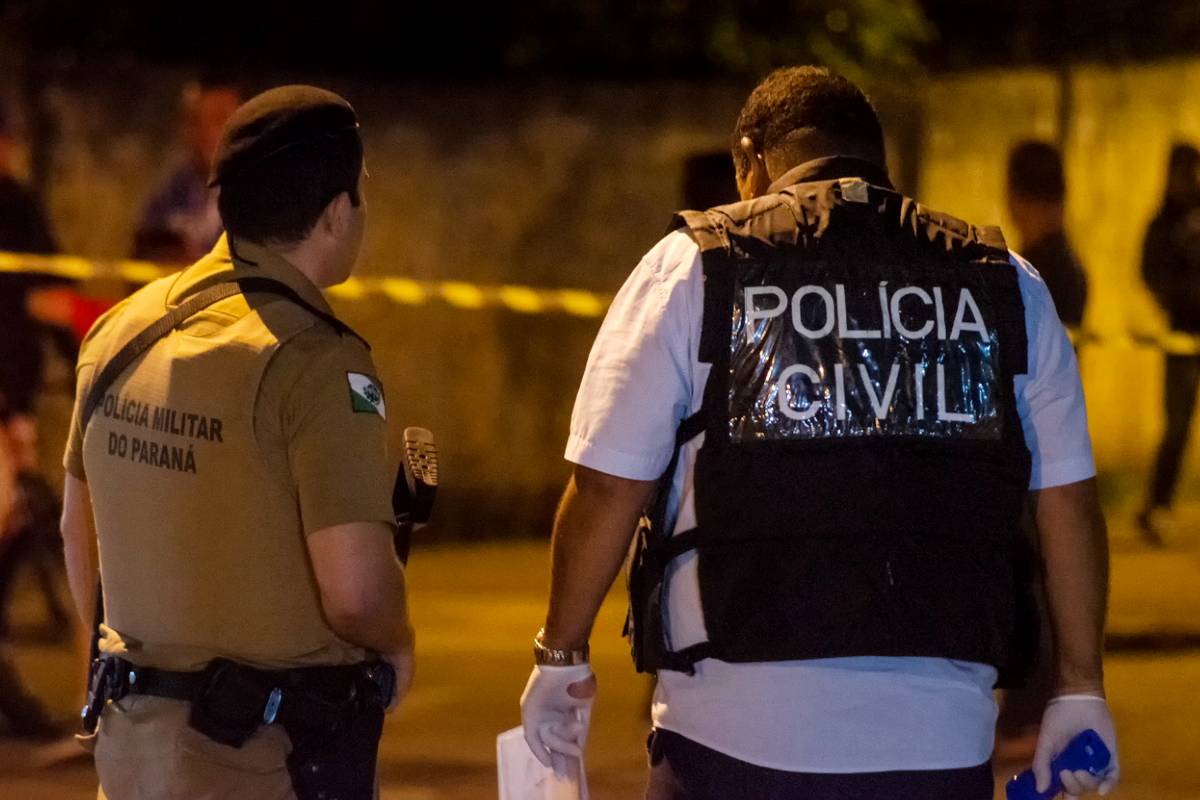 Um policial militar e um policial civil do Paraná acompanham uma cena de crime