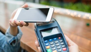cliente usa o celular para pagar uma conta por aproximação