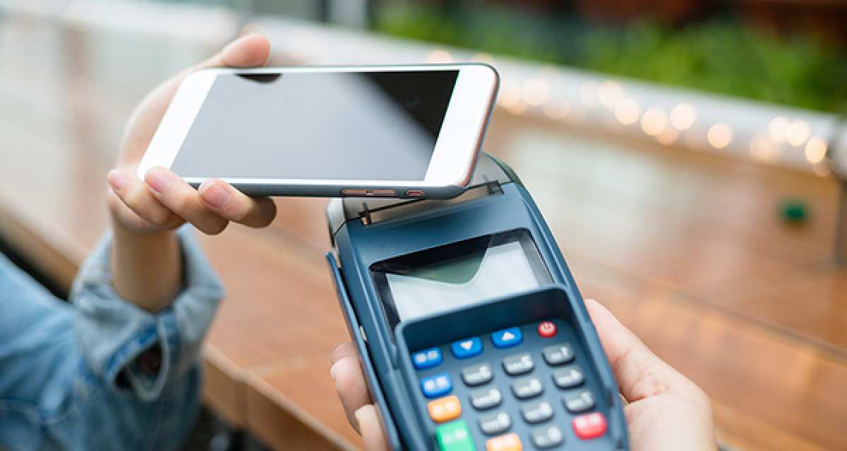 cliente usa o celular para pagar uma conta por aproximação