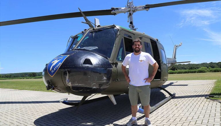 William Starostik posa ao lado do helicóptero UH-1.