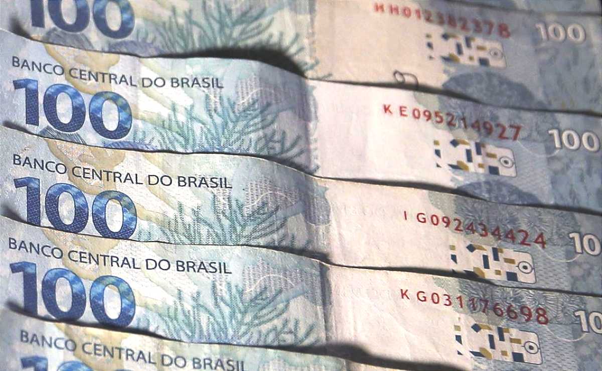 cinco notas de cem reais sobrepostas formando um leque na horizontal