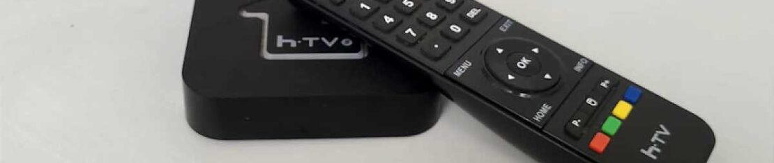 Aparelho TV BOX em cima de uma mesa com o controle remoto de lado