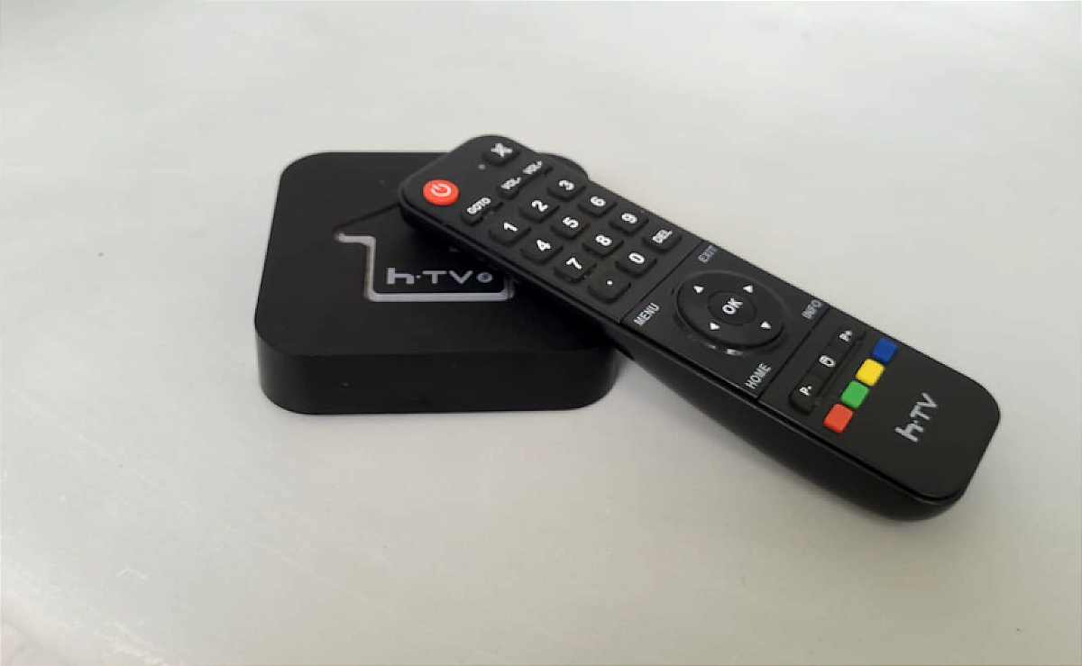 Aparelho TV BOX em cima de uma mesa com o controle remoto de lado