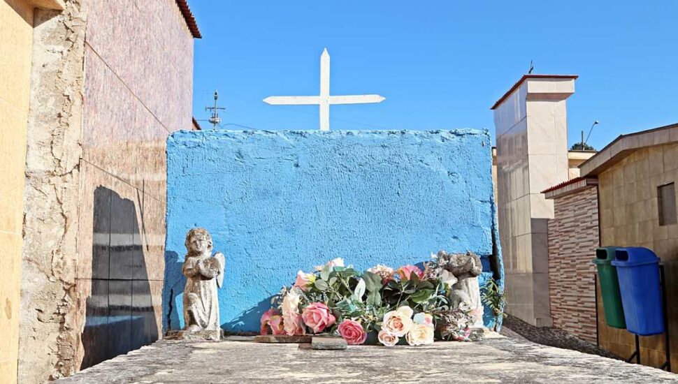 túmulo em Curitiba com detalhes em azul, flores e uma cruz branca.