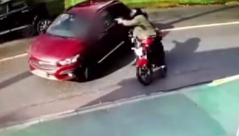 Cena do crime de Ana Paula Campestrini. Homem em uma moto para ao lado do carro vermelho em que ela estava e dispara várias vezes.