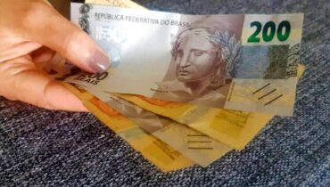 Notas de real num leque. São duas notas de 20 e outra de 200 reais.