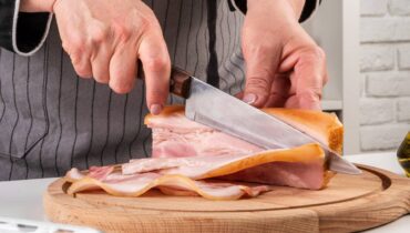 Mulher corta uma bela peça de bacon com uma faca
