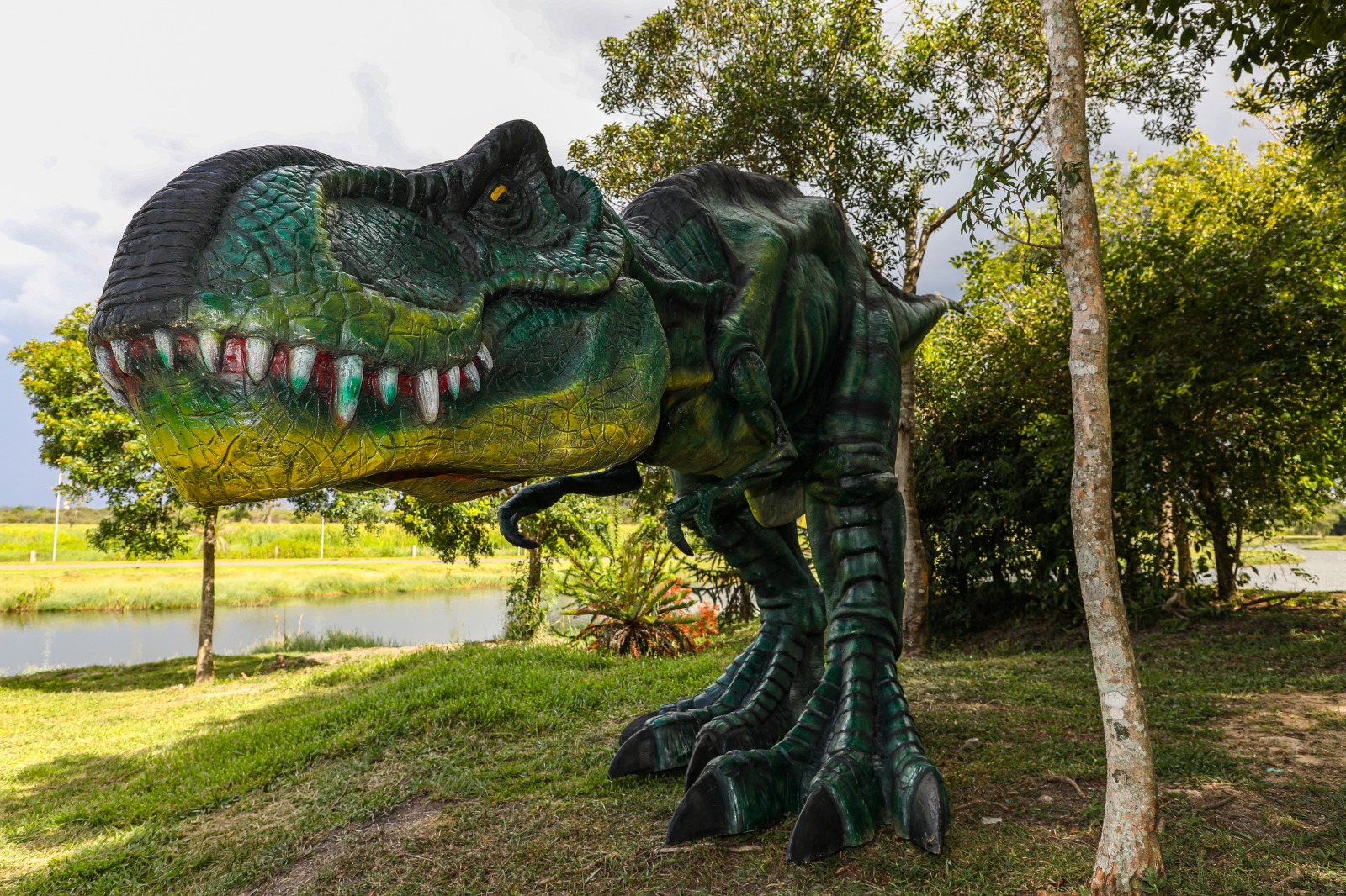 No detalhe, um tiranossauro rex no meio do Parque das Águas de Pinhais