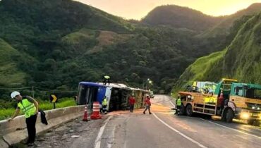 Ônibus tombado na BR-116. Pista interditada e sol nascendo atrás dos morros