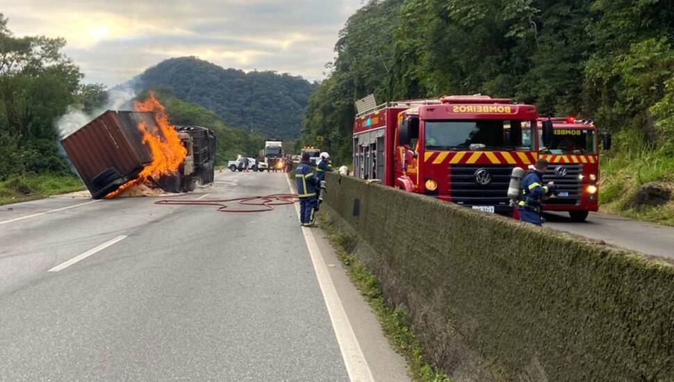 BR-277 com caminhão incendiado no meio da pista e caminhões dos bombeiros em atendimento. Rodovia está interditada.