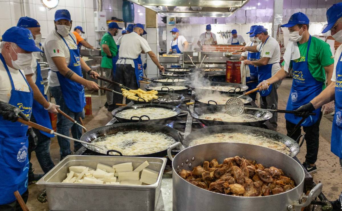 imagem mostra voluntários cozinhando polenta frango em uma cozinha industrial.