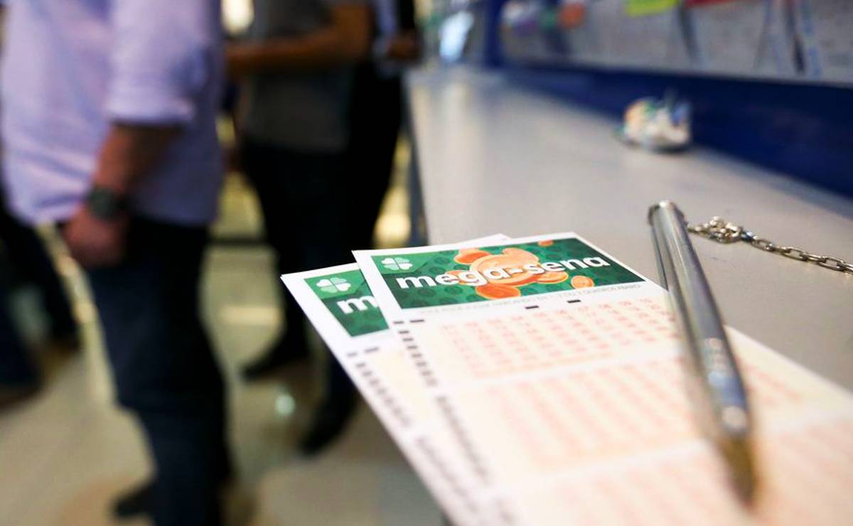 Imagem mostra dois canhotos de aposta da Mega Sena e uma caneta com correntinha em cima.