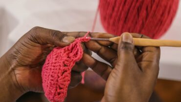 Mãos de artesã fazendo crochê