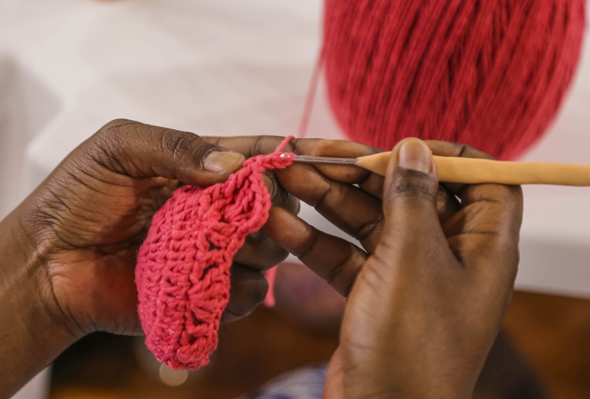 Mãos de artesã fazendo crochê