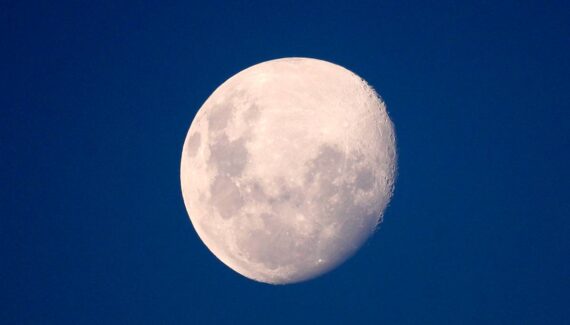 Imagem mostra a Lua em um céu azul.