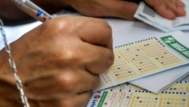 Imagem mostra um apostador da Mega Sena marcando seus números da sorte em um canhoto da Mega Sena
