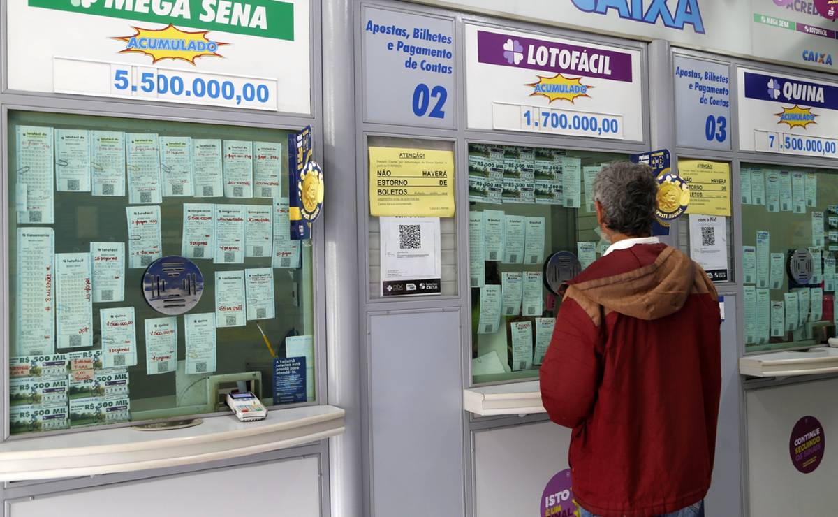 Imagem mostra o guchê de apostas de uma lotérica de Curitiba. Um homem usando uma blusa vermelha faz aposta