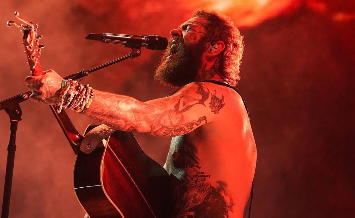 Imagem mostra o cantor Post Malone com um violão em um show ao vivo.