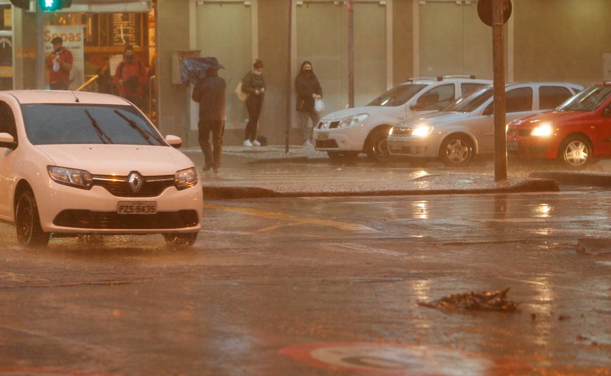 Imagem mostra um carro em meio a um temporal a noite em Curitiba.