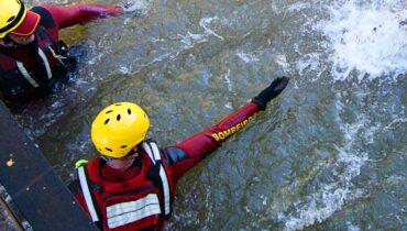 Imagem mostra um bombeiro dentro de um rio para um salvamento.