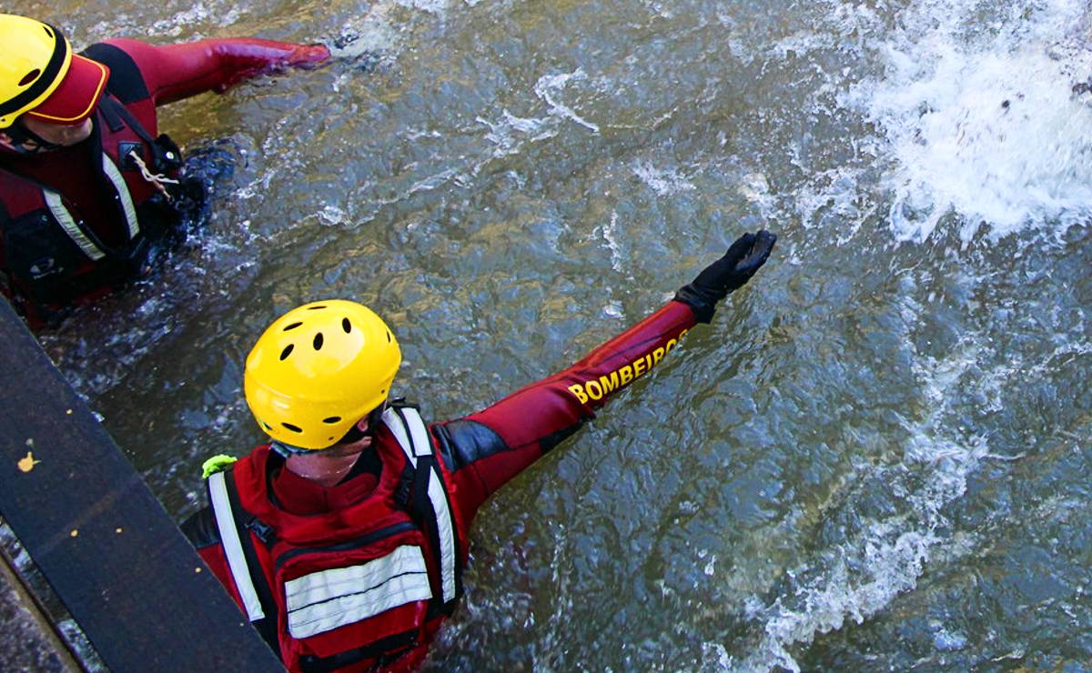 Imagem mostra um bombeiro dentro de um rio para um salvamento.