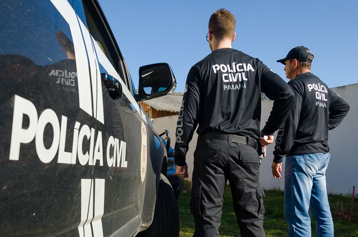 Dois poiciais ao lado de uma viatura da polícia civil do Paraná