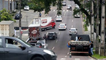 Imagem mostra carros circulando em uma movimentada rua de Curitiba