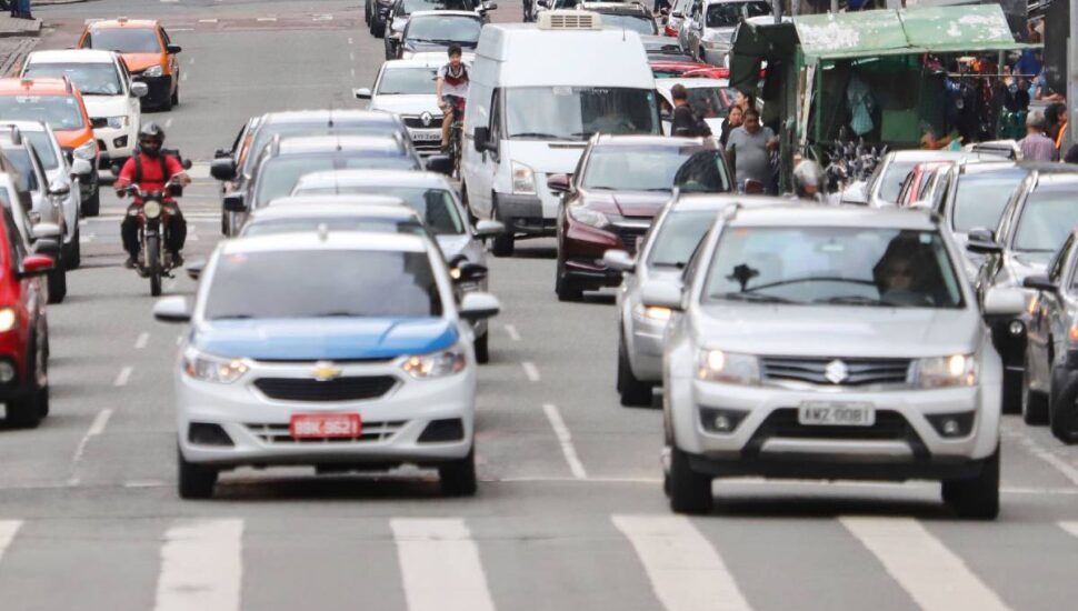 Imagem mostra carros circulando por uma rua movimentada de Curitiba.