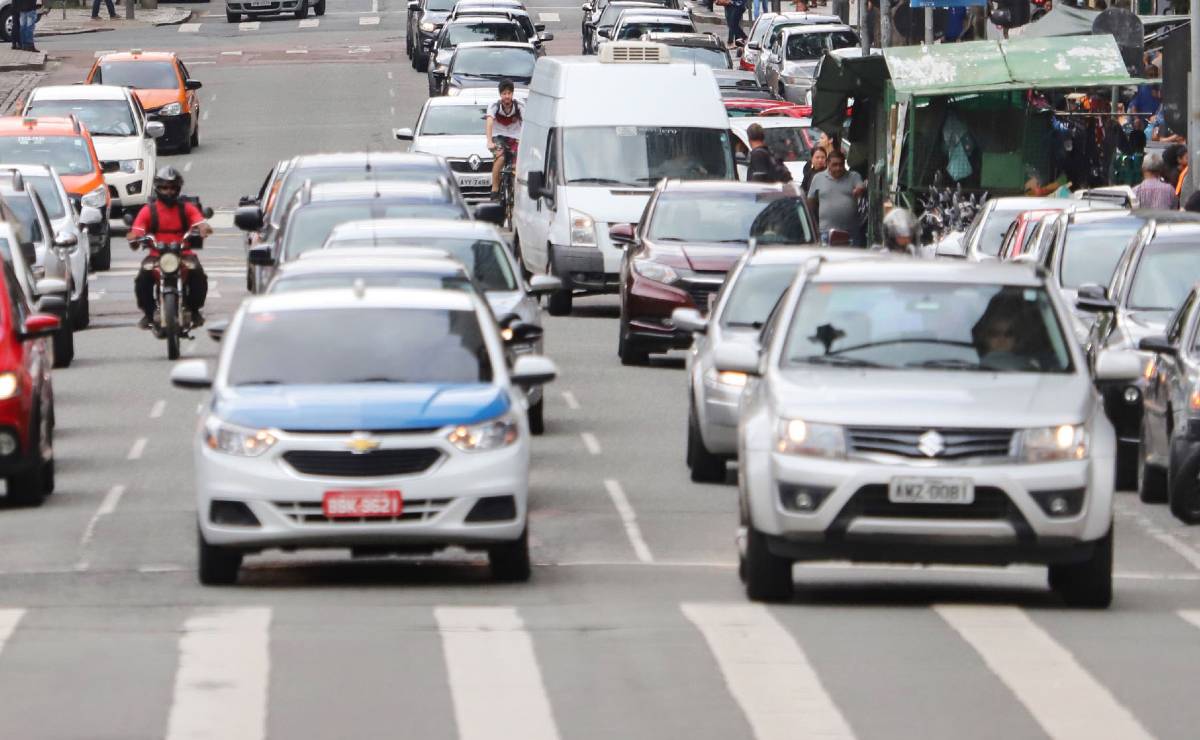 Imagem mostra carros circulando por uma rua movimentada de Curitiba.