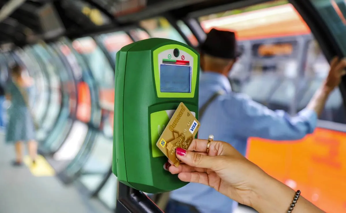 Imagem mostra uma mulher pagando passagem com cartão de crédito em Curitiba