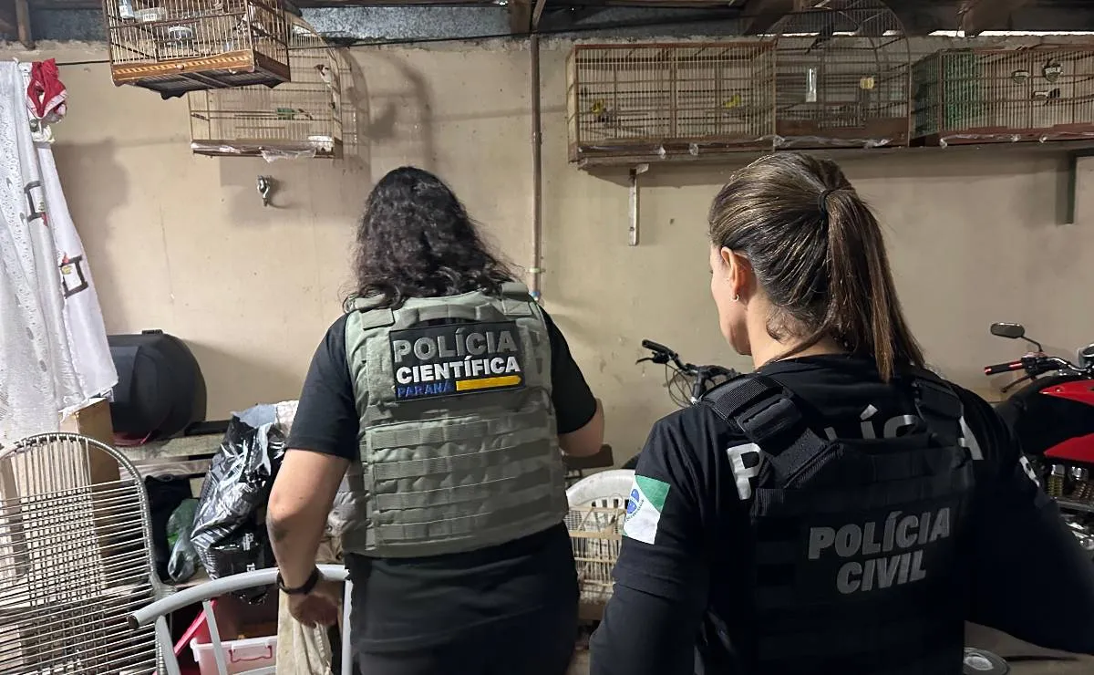 Imagem mostra duas policiais civis em uma casa com gaiolas ao fundo