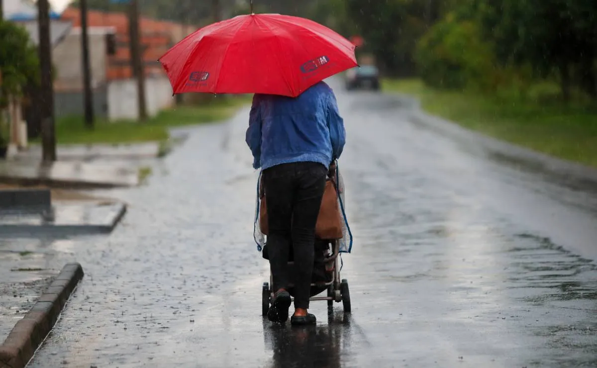 imagem mostra uma pessoa com um guarda-chuva vermelho em Curitiba