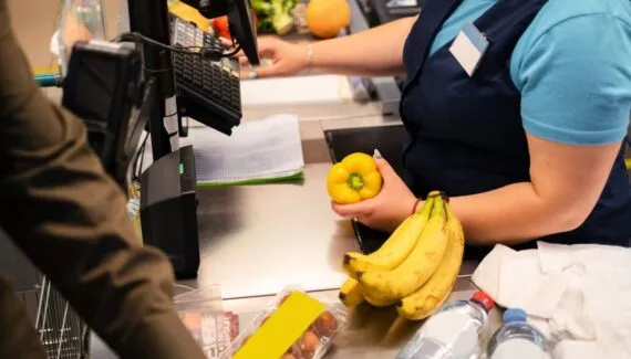 imagem mostra uma mulher trabalhando como caixa de supermercado.